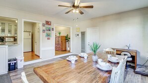 A spacious dining area with a wooden table set for four, a ceiling fan, and a view into the kitchen. - Dog-friendly Albuquerque Home: 1 Mi to U of NM! (Albuquerque)