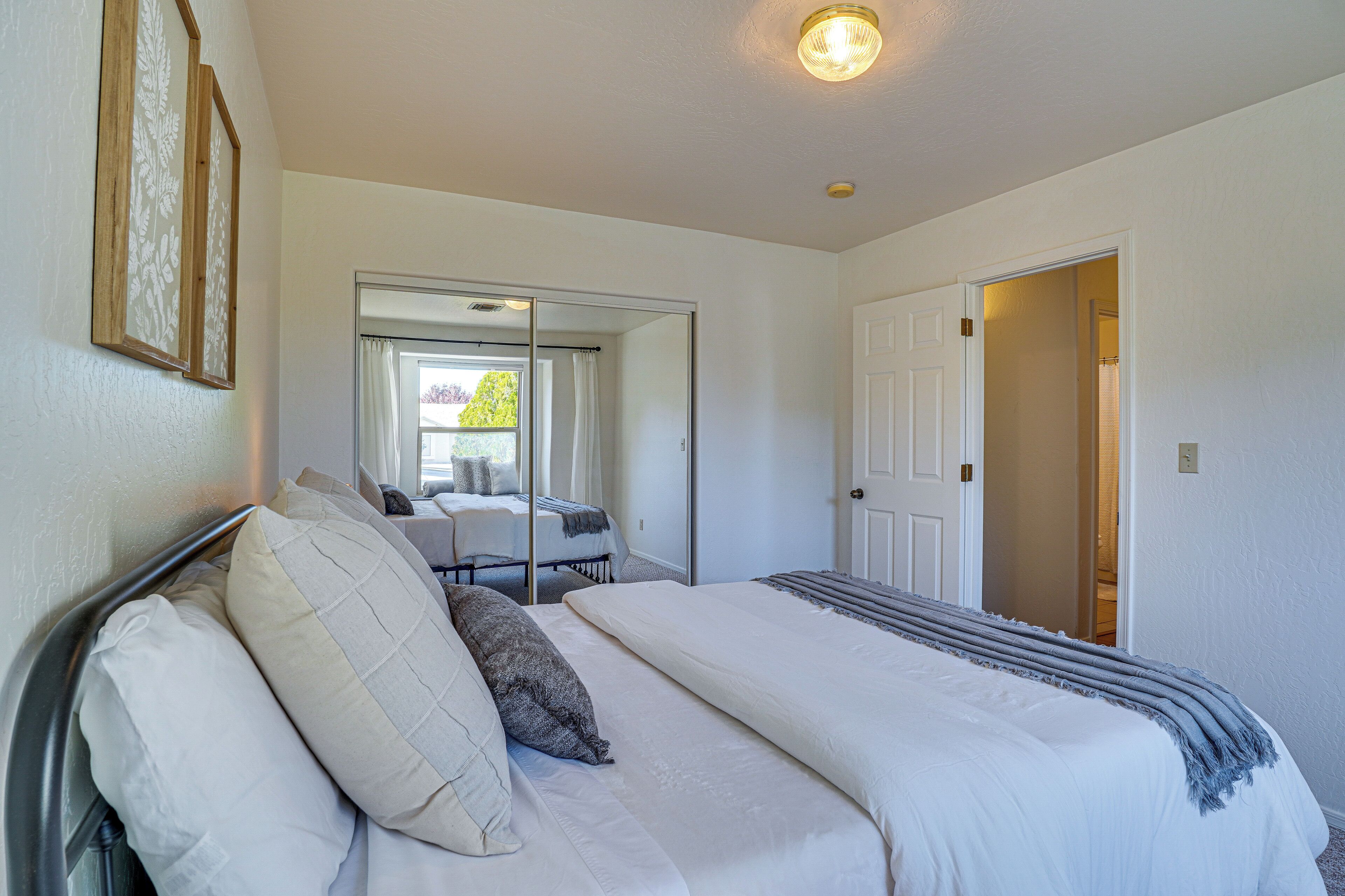 Een slaapkamer met een bed, een spiegel en een deur naar een andere kamer.