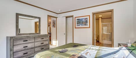Un dormitorio con una cama grande, un tocador, un espejo y una puerta que da al baño.