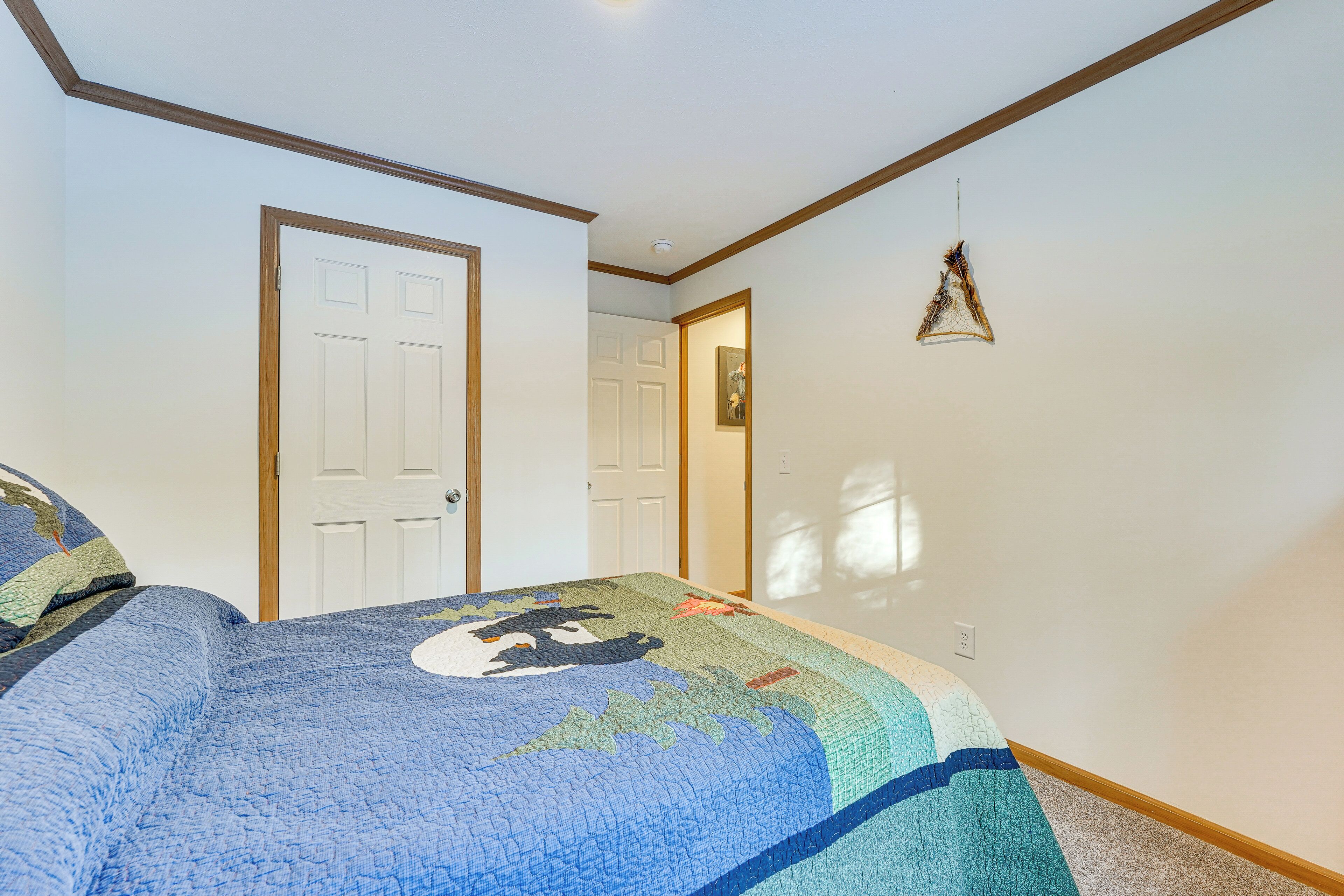 Een slaapkamer met een groot bed, twee deuren en een hanglamp.