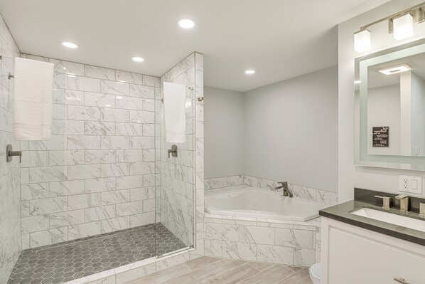 Un baño moderno con ducha, bañera y tocador con espejo.