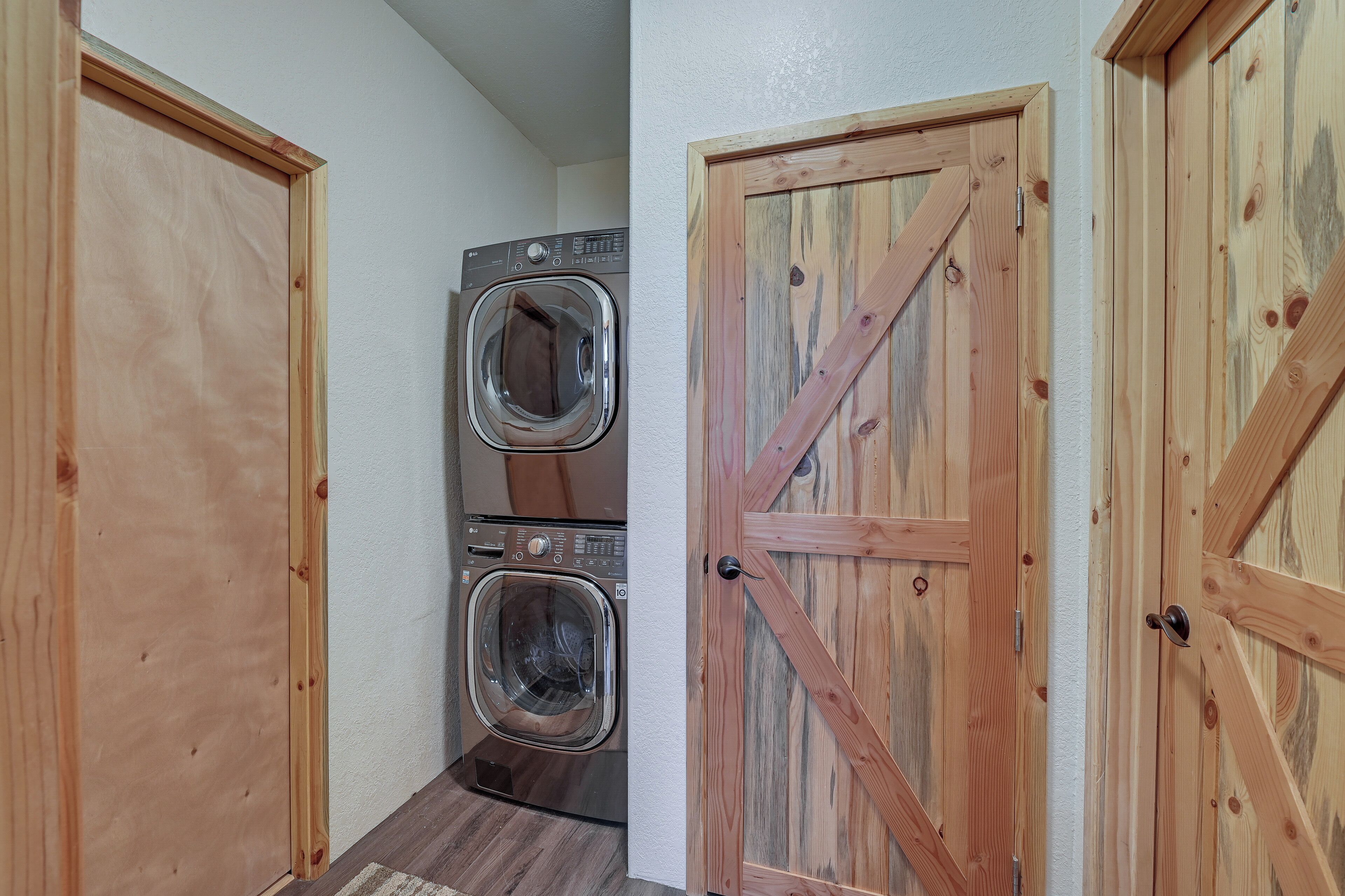 A laundry room with two stacked front-loading washing machines and wooden doors.