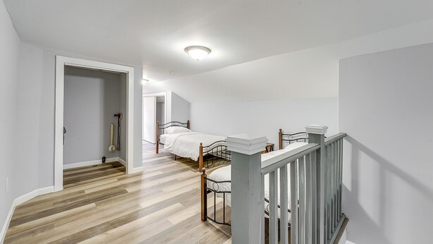 A spacious room with a wooden floor, a white ceiling, and a staircase with a railing.