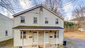A two-story house with a front porch, a small front yard, and a visible front door.
