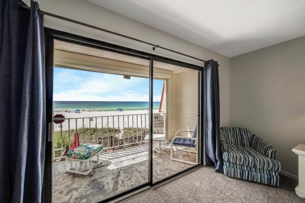 Ein Zimmer mit einer Schiebeglastür, die zu einem Balkon mit Blick auf den Strand führt.