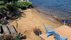 Une plage avec une terrasse en bois, des chaises bleues et une table de pique-nique.