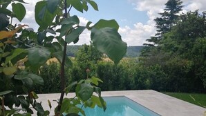Piscina com vista para uma paisagem arborizada e céu claro.