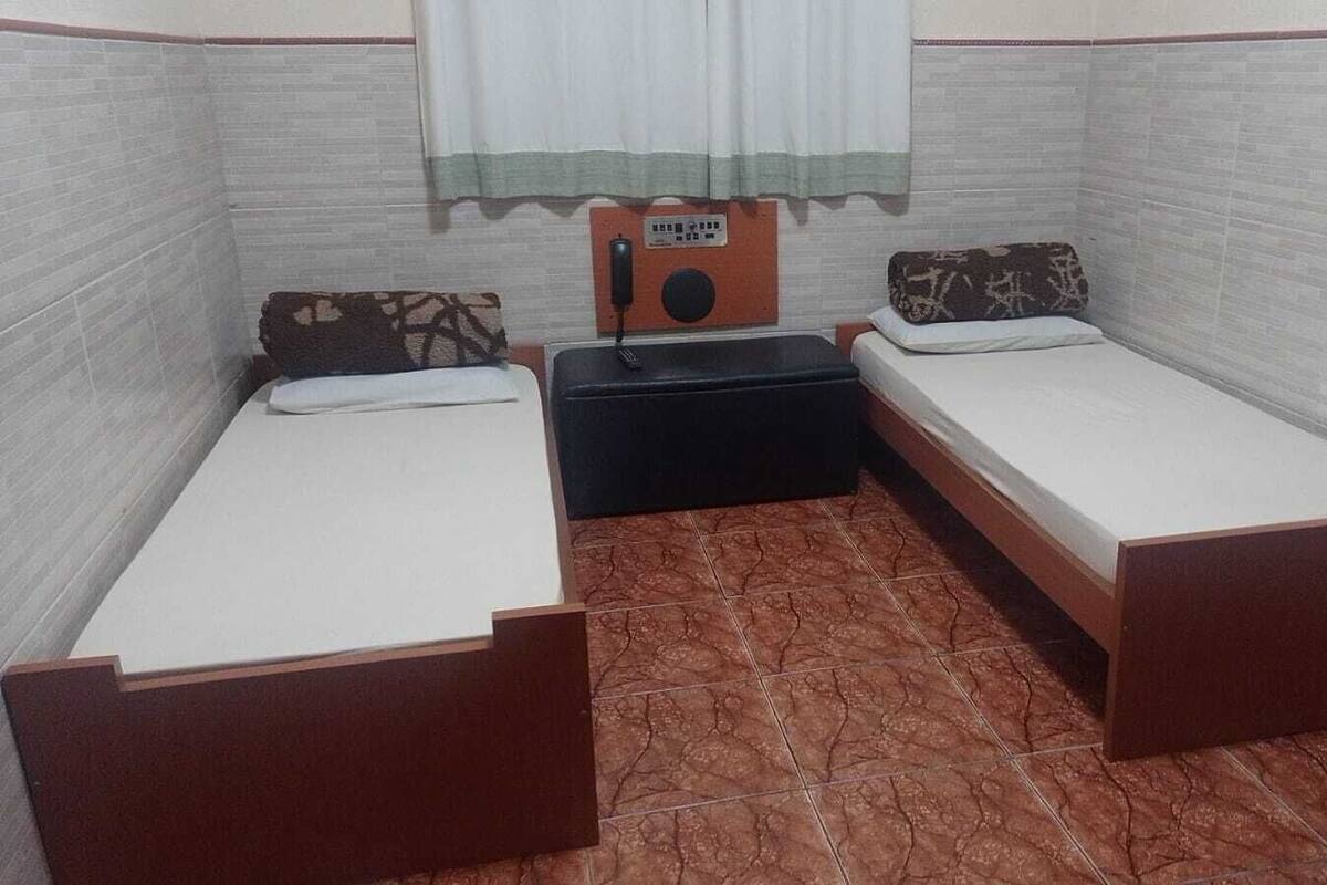 A small room with two single beds, a small table, and a radio.