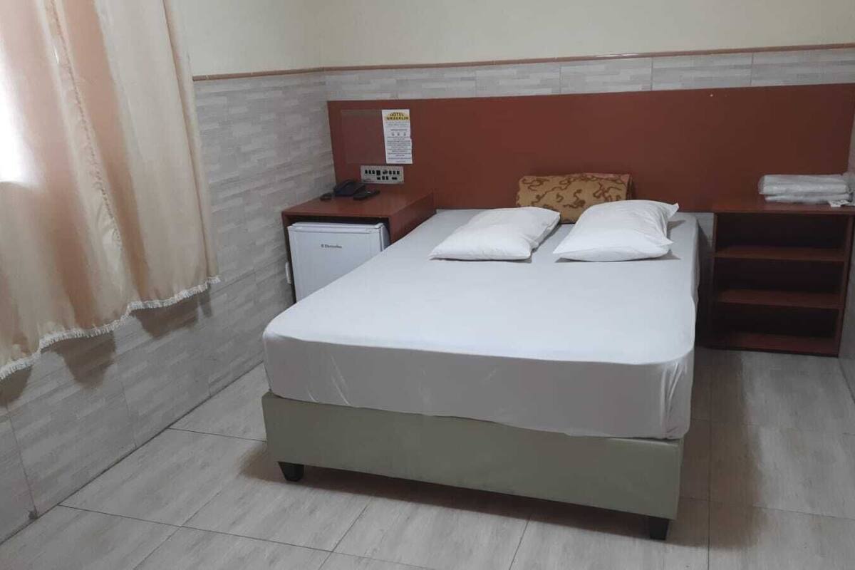 A single bed with white bedding in a hotel room.