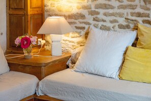 Ein Schlafzimmer mit Steinwand, Nachttischlampe, Blumen in einer Vase und zwei Kissen.