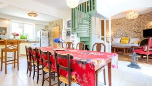 A dining area with a table set for six, a staircase, and a living room with a sofa and television.
