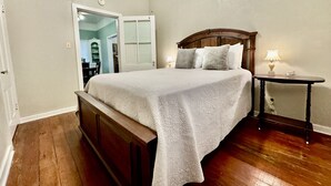 A bedroom with a wooden bed, a bedside table, and a mirror.