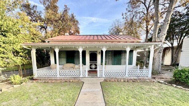 A two-story house with a porch, a front door, and a small front yard.