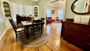 A dining area with a wooden table and chairs, a dark wooden dresser, and a mirror on the wall.