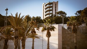 A modern building with multiple balconies and a palm tree-lined pathway. - Modern sea Front Sea Waves (Alicante)