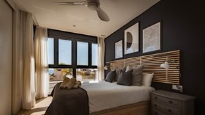 A modern bedroom with a large bed, a nightstand, a ceiling fan, and a view of the outdoors. - Modern sea Front Sea Waves (Alicante)