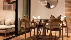 A modern living room with a sofa, a dining table with chairs, and a round mirror on the wall. - Longbeach Smart Muchavista (El Campello)