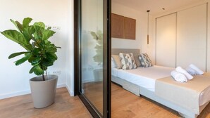 A modern bedroom with a bed, a potted plant, and a sliding door. - Longbeach Smart Muchavista (El Campello)