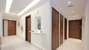 Un pasillo moderno con puertas de madera, un mostrador de recepción blanco y un candelabro en el techo.