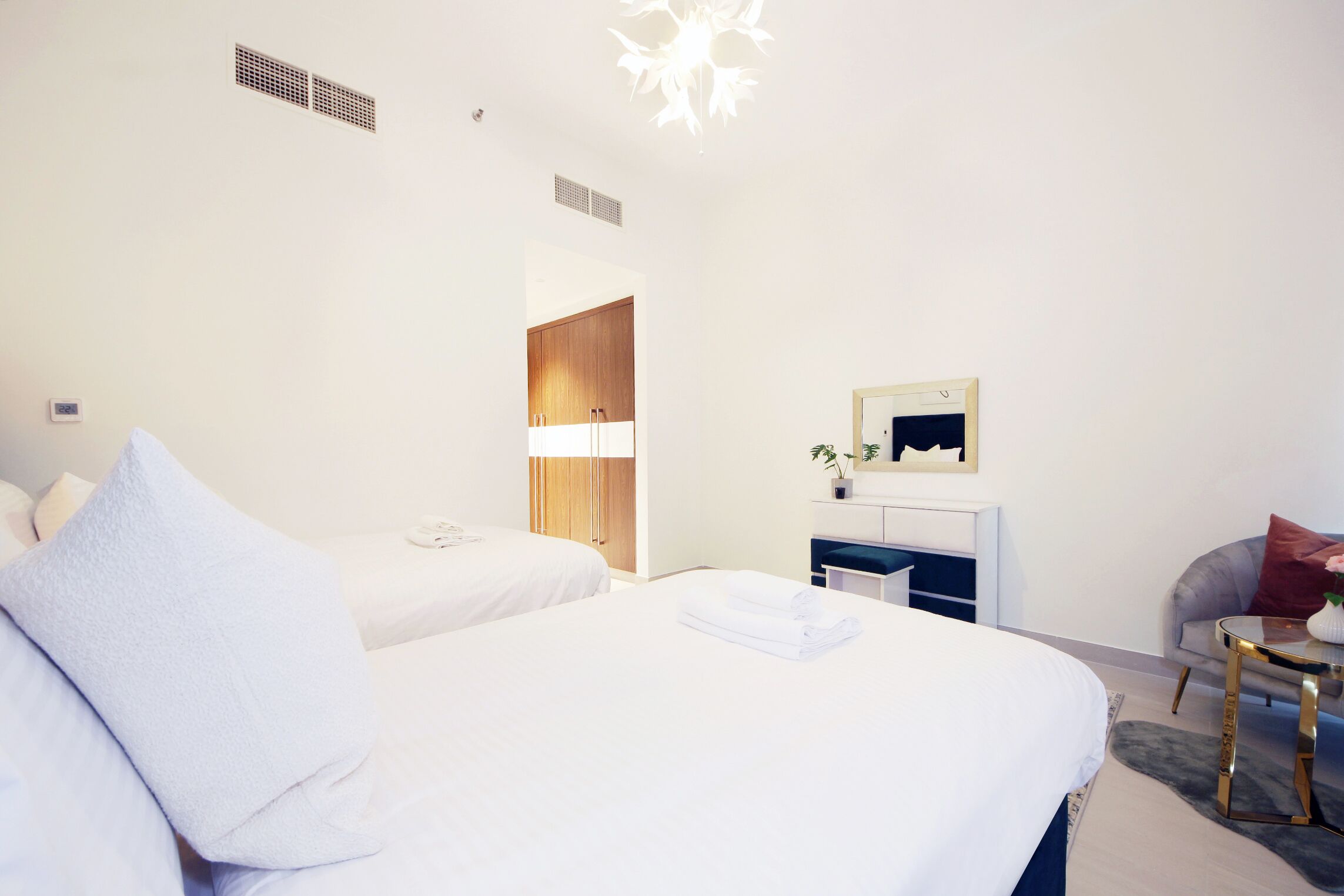 A hotel room with two beds, a small desk, a chair, and a mirror.