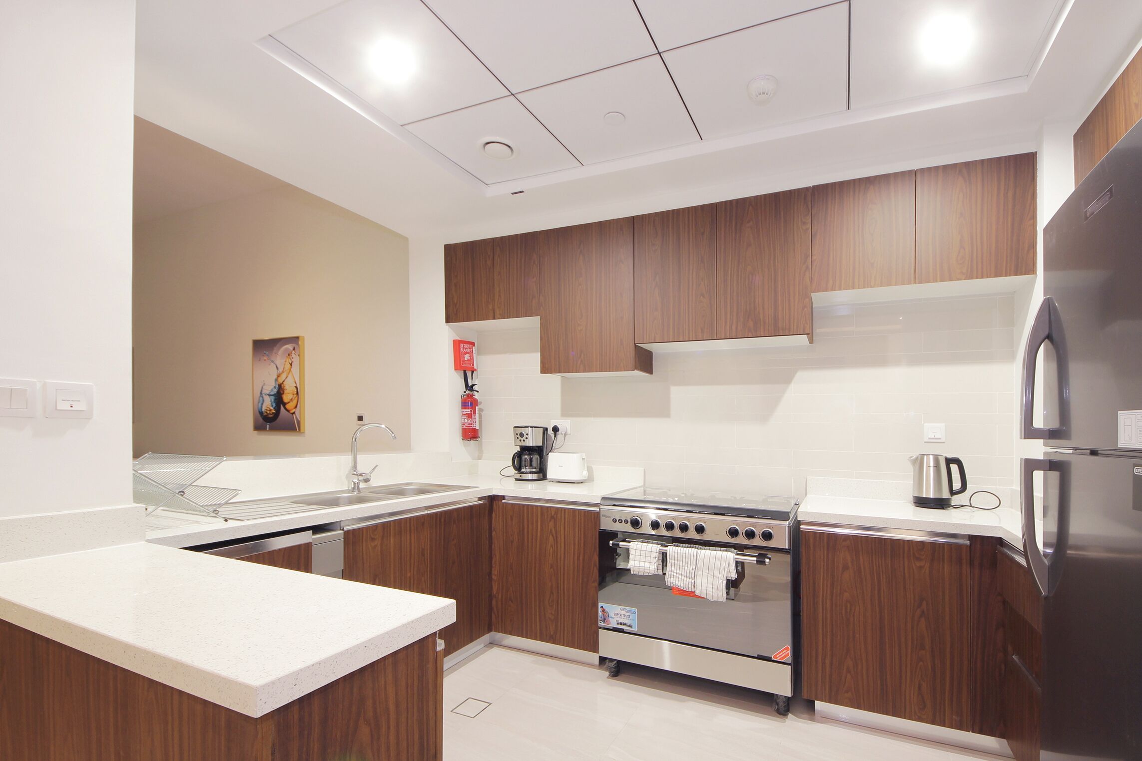 Een moderne keuken met houten kastjes, roestvrijstalen apparatuur en een wit aanrecht.