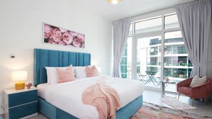 Un dormitorio moderno con una cama grande, una mesita de noche, una silla y un balcón con vistas a la ciudad.