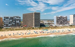 Un hôtel situé sur la côte, composé de plusieurs immeubles de grande hauteur, avec une plage de sable fin et un ciel bleu dégagé.
