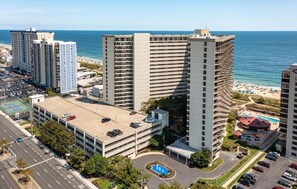 Un hôtel de grande hauteur, avec de nombreux étages, un parking et une vue sur la plage.