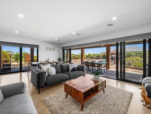 A spacious living area with a grey sofa, a wooden coffee table, and a dining set. - Dan's Rise - With luxurious pool (Mansfield)