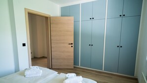 Quarto de hotel com duas camas, um guarda-roupa de madeira e um guarda-roupa azul.