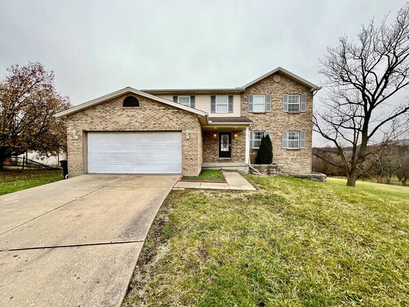 A two-story house with a garage, a front porch, and a well-maintained lawn.