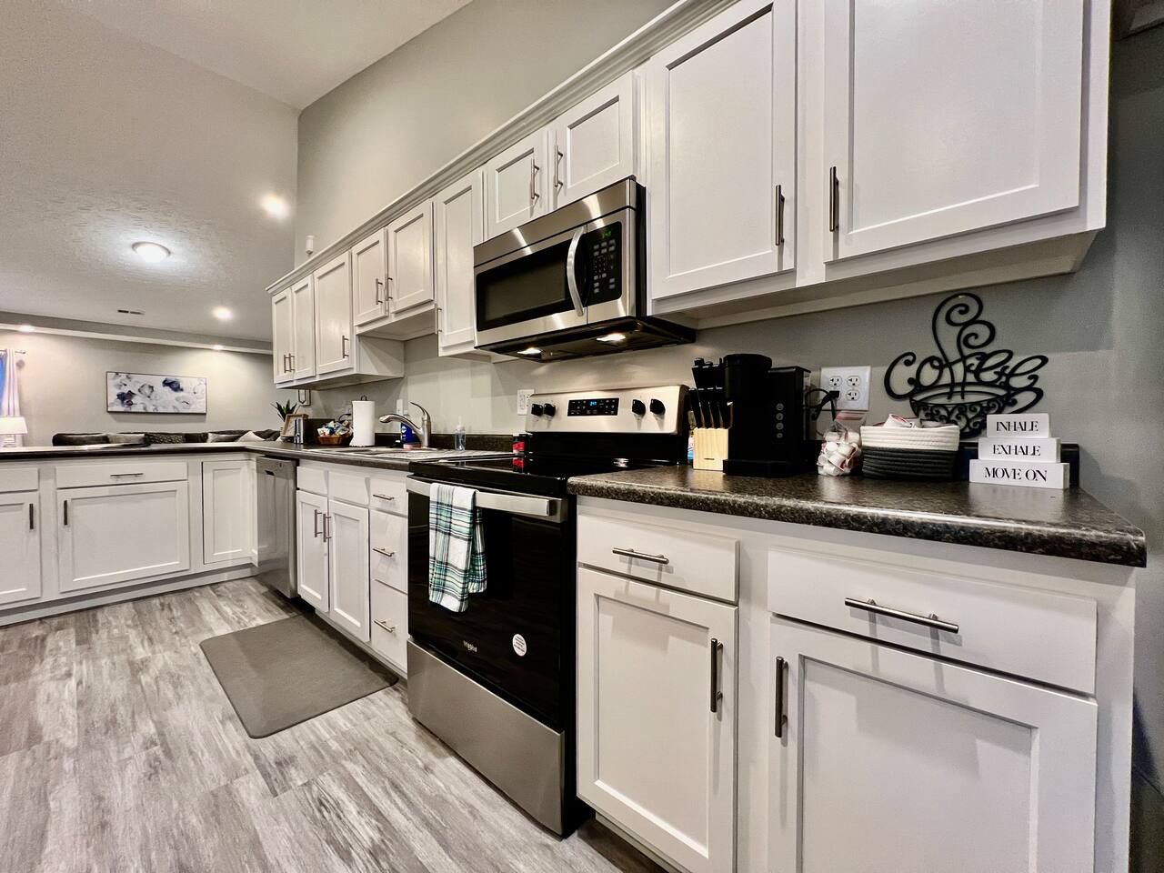 A modern kitchen with white cabinetry, stainless steel appliances, and a granite countertop.