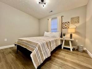 A bedroom with a bed, a nightstand, a lamp, and a window with curtains. - Nicest New construction Home in Middletown, Ohio (Middletown)