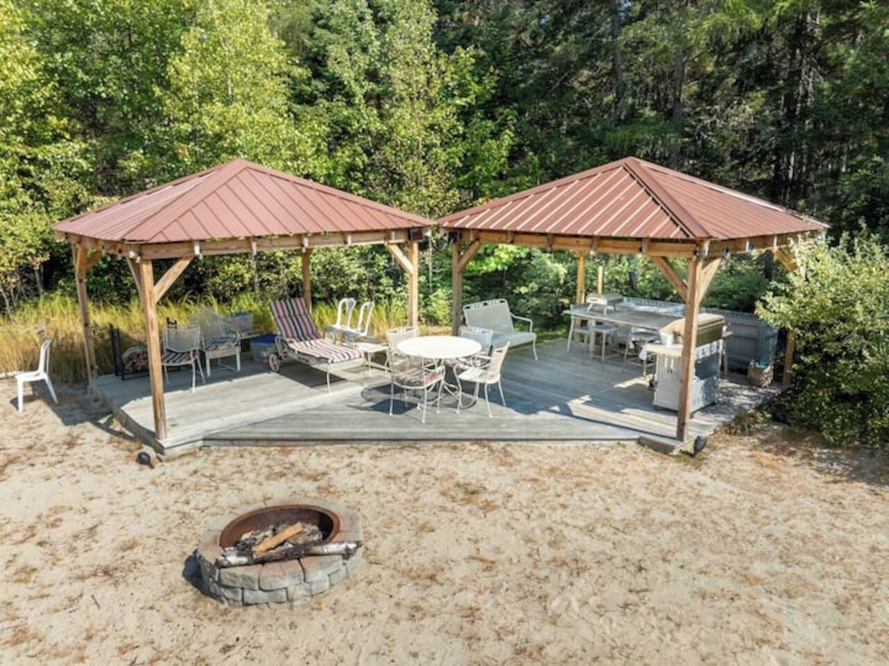 A covered outdoor area with a fire pit, seating, and a deck.