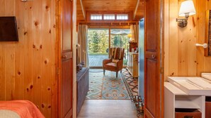 A wooden cabin interior with a cozy living area, a dining space, and a view of the outdoors. - Sunny Waterfront Cottage at FarAway Pond (Whitefield)