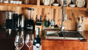 A kitchen counter with a wine bottle, two glasses, and a box of caramel cookies. - Sunny Waterfront Cottage at FarAway Pond (Whitefield)