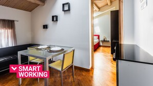 Une pièce moderne et bien éclairée, avec une table à manger en verre, un canapé et un coin cuisine.