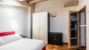 Une chambre à coucher comprenant un lit, une armoire, un bureau et une porte donnant sur un placard.