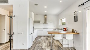 Een moderne keuken met witte kasten, een houten aanrecht en een bar met witte stoelen.