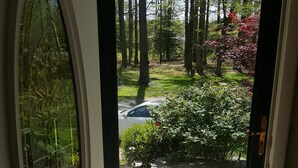 Une porte donnant sur un jardin avec un chemin de pierre, entouré de verdure et d’arbres.