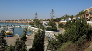 Una marina con barche, una passeggiata sul lungomare e palazzi con balconi.