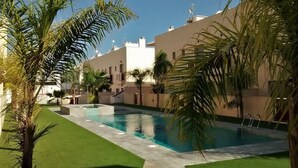 Una piscina circondata da palme e un edificio con tetto piatto.
