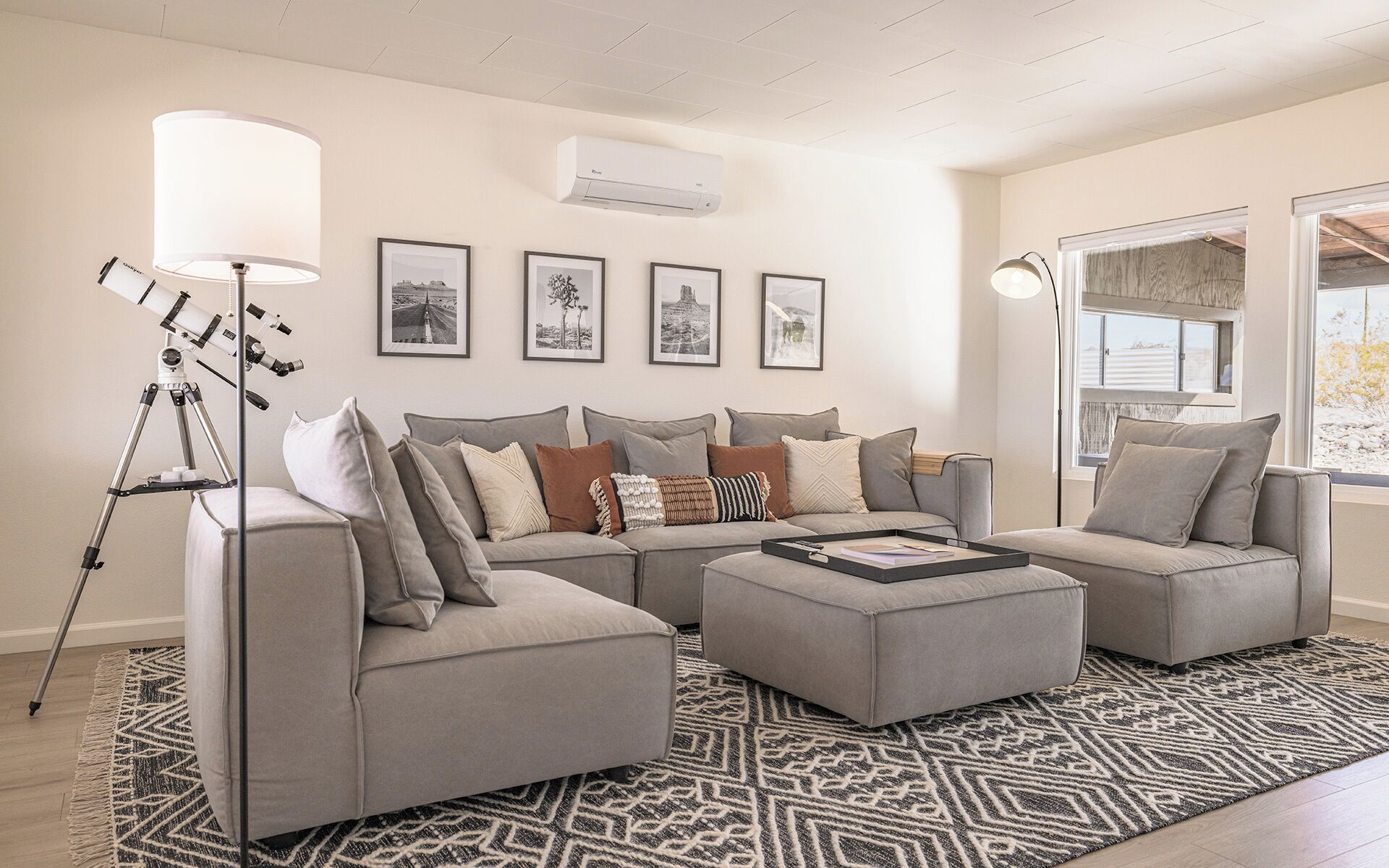 Una sala de estar moderna con un sofá modular, una lámpara de pie y cuadros enmarcados en la pared.