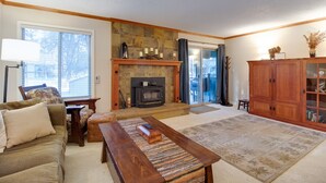 A cozy living room with a fireplace, a sofa, a coffee table, and a wooden cabinet.