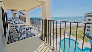 A balcony with a pool, lounge chairs, and a view of the beach and ocean. - Summer Winds B-601, Oceanfront Condo in Indian Beach, NC! (Indian Beach)