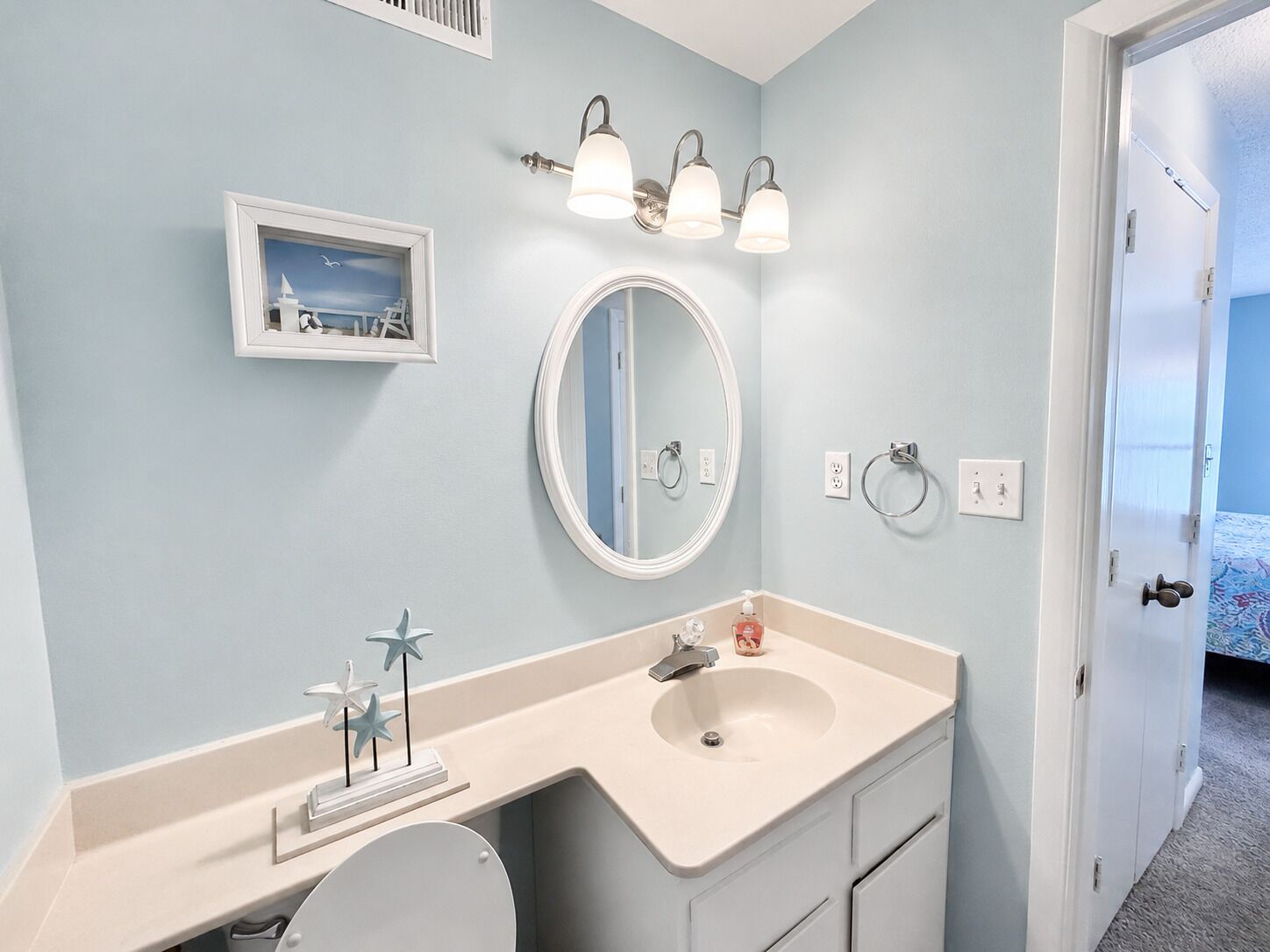 A bathroom with a sink, mirror, and a framed picture on the wall.