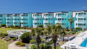 Et turkis hotel med flere etager, altaner, swimmingpool og palmer.