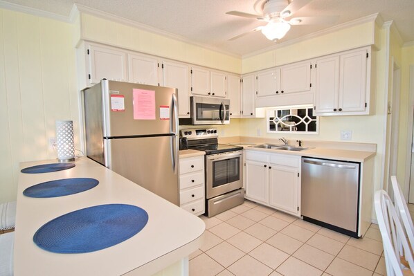 A kitchen with white cabinets, stainless steel appliances, a microwave, oven, and dishwasher.