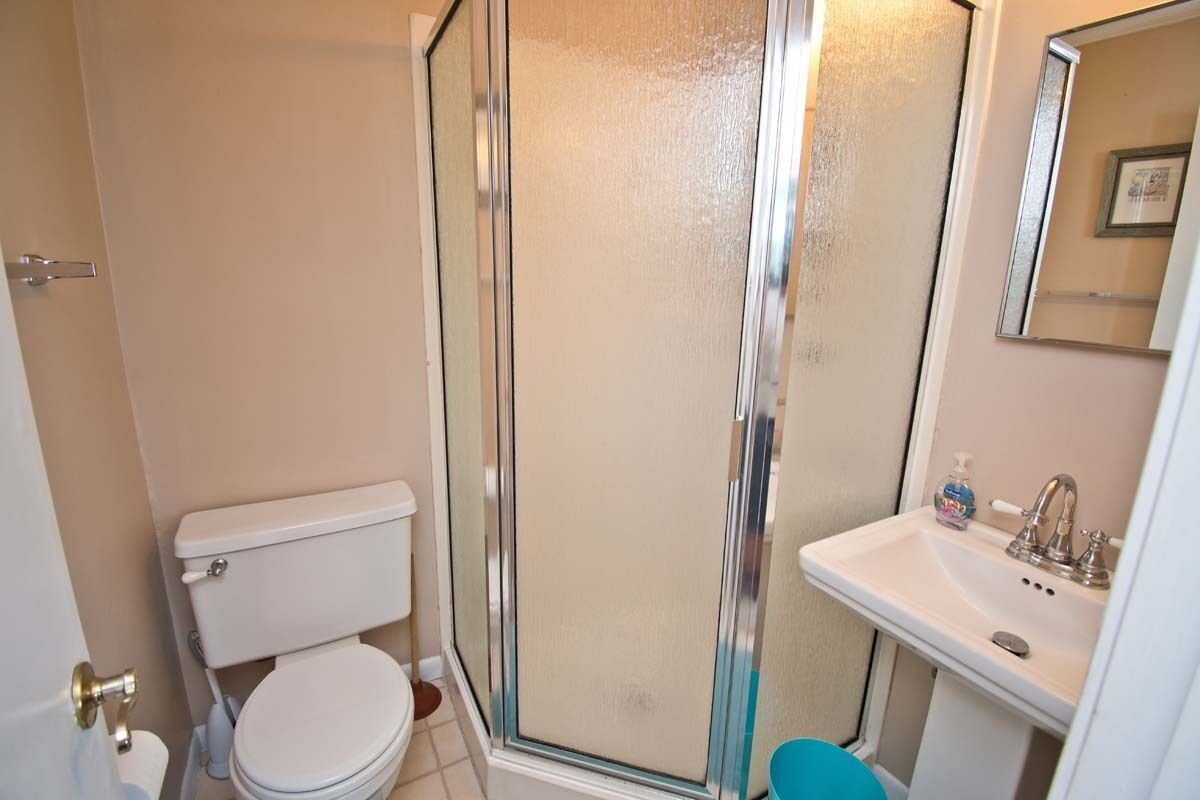 Ein Badezimmer mit Toilette, Duschkabine und Waschbecken mit Spiegel.