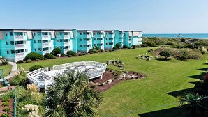 Un hôtel moderne à la façade bleu clair, doté de nombreux balcons et d’une pelouse bien entretenue avec un petit espace piscine.